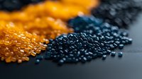 Colorful plastic polymer granules in orange and navy blue shades on dark background, macro shot showing industrial raw materials for manufacturing process.