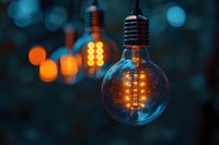 Vintage glowing edison bulbs with warm orange filaments against blurred dark blue background creating atmospheric bokeh lighting effect.