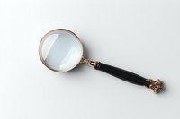 Vintage magnifying glass with gold frame and black handle on white background, perfect for detective themes and search concepts.