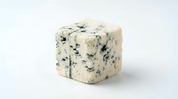 Creamy blue cheese wedge with distinctive veining and mold cultures, showcasing rich texture for culinary, food styling, and gourmet ingredient applications.