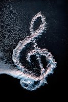 Treble clef formed by white sea foam against dark water, creating natural musical symbol for music-themed projects and artistic compositions.