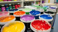 Vibrant screen printing ink containers in multiple colors arranged in rows, showing glossy paint surfaces ready for textile and paper applications in professional print shop.