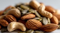 Mixed nuts and seeds collection featuring almonds cashews and pumpkin seeds arranged on neutral background for healthy snacking and nutrition concepts.