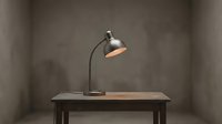 Industrial desk lamp with metal shade on wooden table against concrete wall, suitable for office and home interior design projects.