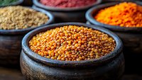 Colorful spices and lentils displayed in traditional clay bowls at spice market. Vibrant orange, red and yellow seasonings for cooking and culinary use.