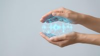 Hands protecting glowing digital globe with network connections representing global technology security and data protection concepts.
