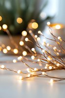 Glowing fairy lights on copper wire create magical bokeh effect against soft white background, bringing warmth and festive atmosphere to holiday decor.