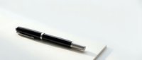 Black fountain pen with silver accents resting on white paper sheet against clean background for business writing and professional correspondence.