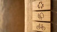 Wooden eco-friendly symbols engraved on natural wood blocks showing recycling, leaf and bicycle icons for sustainable living and environmental awareness.