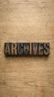 Vintage wooden letterpress blocks spelling ARCHIVES on natural wood grain background for typography and design projects.