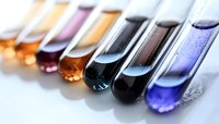 Colorful chemical solutions in test tubes arranged in row showing gradient from amber to purple, black, and blue for scientific research and laboratory analysis.