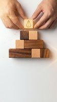 Male hands placing wooden block with light bulb icon on stacked wood blocks, representing business growth, innovation strategy, and sustainable development planning.