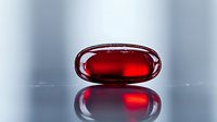 Red transparent gel capsule pill on reflective surface with soft focus background, pharmaceutical and medical concept showing medicine and healthcare innovation.