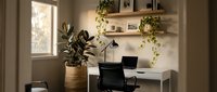 Modern home office workspace with laptop computer, plants and natural lighting creating productive work environment for remote professionals.