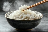 Steaming hot white rice in black ceramic bowl with wooden chopsticks, captured with rising steam against dark background, food photography for menu design.