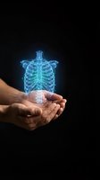 Hands holding glowing blue holographic human ribcage and spine anatomy projection on black background for medical education and healthcare technology concepts.