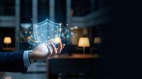 Businessman holding glowing digital shield with network connections, representing cybersecurity, data protection, and secure technology solutions for enterprise business.