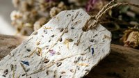 Handmade paper with embedded wildflower petals and botanical fibers, showcasing natural textures and earthy tones for craft, design, and artisanal projects.