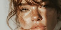 Young woman with freckles and natural makeup looking at camera with soft lighting for beauty and skincare concepts.