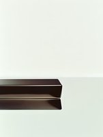Minimalist architectural detail showing two dark brown metal or wooden parallel beams against light background, creating strong geometric lines and shadows.