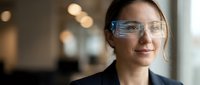 Professional woman wearing smart glasses with digital interface display in modern office environment for technology and business applications.