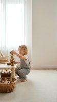 Happy blonde toddler girl playing with wooden toys in bright minimalist nursery room with natural light and wicker baskets for educational development.