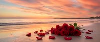 Red roses scattered on sandy beach at sunset with romantic golden sky and ocean waves creating dreamy atmosphere for love and romance concepts.