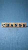 Wooden alphabet blocks spelling CHANGE on blue denim background for business transformation and personal development concepts.