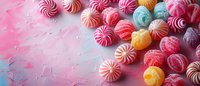 Colorful striped hard candies and sugar coated fruit drops scattered on pink textured background with copy space. Sweet festive confectionery flat lay.