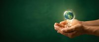 Hands holding glowing Earth globe on green background representing environmental protection, sustainability and global responsibility for planet care.