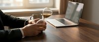 Professional businessman working remotely with laptop and coffee cup on wooden desk in modern home office setup for productivity and work-life balance.