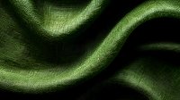 Elegant green silk fabric with soft waves and folds creating dramatic light and shadow play on textured surface. Close-up macro photography reveals intricate textile details.