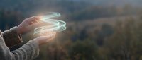 Young woman's hand releasing glowing energy orbs over forest landscape, representing magic, spirituality, healing power, and connection to nature for wellness and meditation concepts.