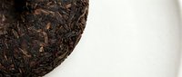 Compressed dark tea cake with aged leaves on white background, isolated for beverage packaging and culinary design use.