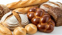 Fresh artisan bread assortment with baguettes, sourdough loaves, braided challah and dinner rolls on white background for bakery menu design.