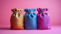 Three colorful burlap drawstring pouches in orange, blue and purple arranged on pink background for gift packaging and storage solutions.