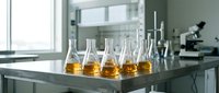 Laboratory glassware with amber liquid samples on metal table in modern research facility for scientific analysis and testing experiments.
