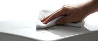Hand wiping white surface with cloth removing dust and dirt particles for household cleaning and maintenance tasks.
