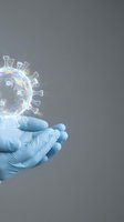 Medical professional hands in blue gloves holding transparent virus model with rainbow light effects on gray background for healthcare education.