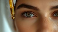 Young woman applying golden facial serum with dropper for skincare routine, close-up beauty treatment with natural glowing skin and healthy complexion.