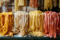 Fresh colorful homemade pasta varieties including classic, saffron yellow, and tomato red fettuccine arranged on display, perfect for authentic Italian cuisine and restaurant menu photography.