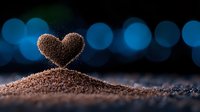 Heart shaped coffee grounds on dark background with blue bokeh lights, romantic coffee concept for cafe, restaurant or coffee shop marketing and social media content.