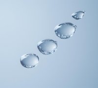 Clear water drops in diagonal line formation on light blue surface, with detailed surface tension and light reflection creating crystalline appearance.