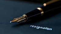 Elegant fountain pen nib close-up with resignation text on dark background, dramatic lighting emphasizes corporate departure and professional transition concept.