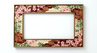 Ornate floral picture frame with pink cherry blossoms and green leaves on brown background, isolated on white for home decor and design projects.