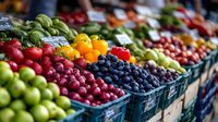 Fresh produce display at farmers market with colorful fruits and vegetables in blue plastic containers, including blueberries, apples, tomatoes and citrus arranged in rows.