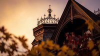 Gothic revival architecture with ornate ironwork and decorative elements during golden hour sunset creating warm atmospheric lighting for historic building photography.