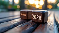 Wooden blocks showing year 2026 on park bench with soft bokeh lights in background creating warm atmospheric mood for future planning concept.