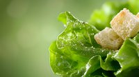 Fresh green lettuce leaf with crispy crouton and salt crystals in macro view against blurred natural background, healthy food concept for restaurant menu.