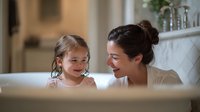 Joyful moment between mother and daughter sharing laughter in modern bathroom with marble countertop, creating warm family atmosphere at home.